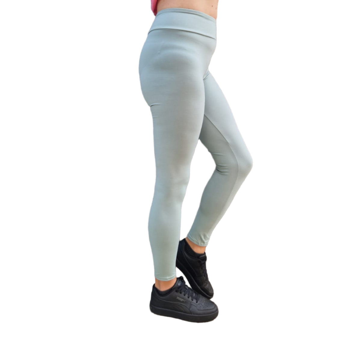 Person wearing light blue leggings and a pink top against a wooden wall.